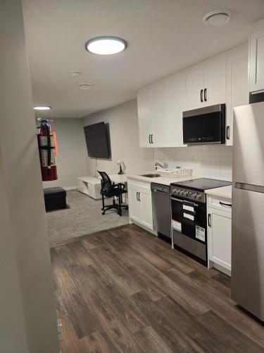 a kitchen with white cabinets and a black appliances at Guest Suite in Southwest Calgary in Calgary