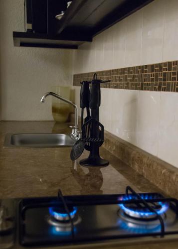 a kitchen counter with a sink and a stove at Hotel Rincon Real Suites in Durango