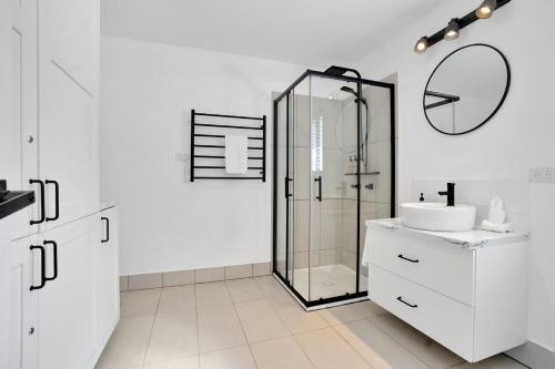 a white bathroom with a shower and a sink at Cozy Cottage at Sunshine Grove in Peachester