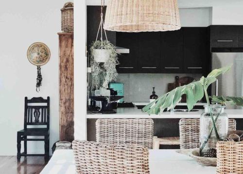 Una cocina con mesa y sillas de mimbre y una cocina con gabinetes negros. en The Tasman Secret, en Manyana