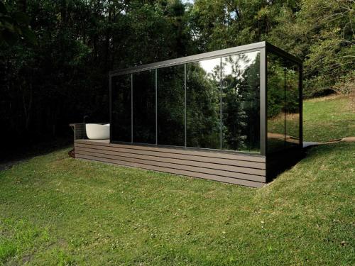 a glass house with a tub in the grass at Luxury Mirror Home In Byron Bay in Byron Bay
