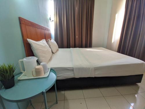 a bed in a hotel room with a side table at Midah Inn Hotel Puchong in Batu Caves