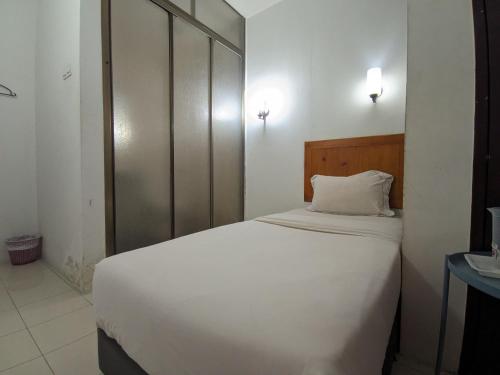 a bedroom with a white bed with a wooden headboard at Midah Inn Hotel Puchong in Batu Caves