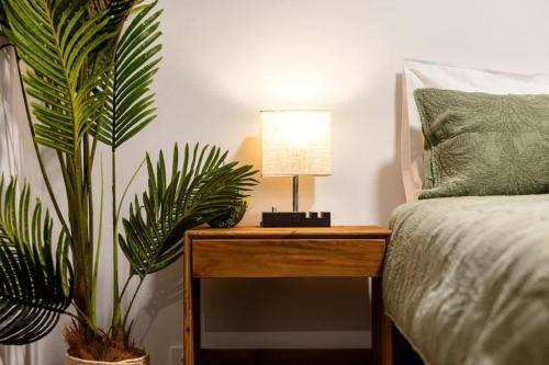 a bed with a table with a lamp and two plants at Seednest Barossa Vineyard Escape in Tanunda
