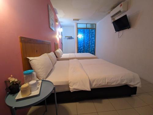 a bedroom with a bed with a table and a television at Midah Inn Hotel Puchong in Batu Caves