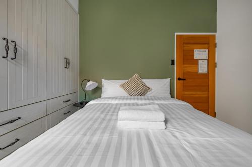 a bedroom with a large white bed with a wooden door at Sunset Mu Style Inn in Xiaoliuqiu