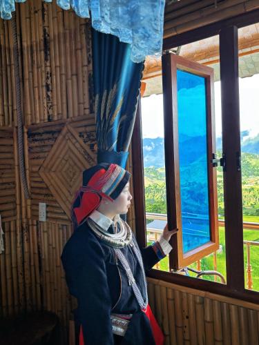 a woman in a costume looking out of a window at Homestay Trúc Sơn in Hong Ha