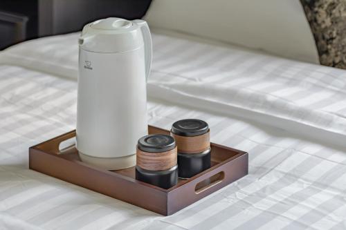 a wooden tray with a thermos on a bed at Sunset Mu Style Inn in Xiaoliuqiu