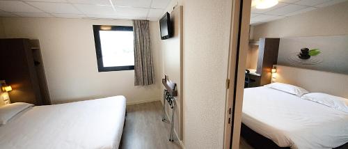 a hospital room with two beds and a window at The Originals City, Hôtel Clermont-Ferrand Sud Aubière in Aubière