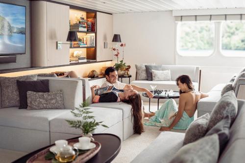 a man and a woman sitting in a living room at Four Seasons Explorer Palau - Cruising Resort in Koror