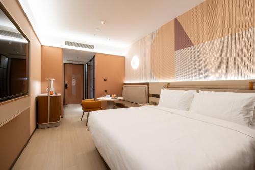 a hotel room with a large bed and a desk at Orange Hotel Beijing Shiliuzhuang Subway Station in Beijing