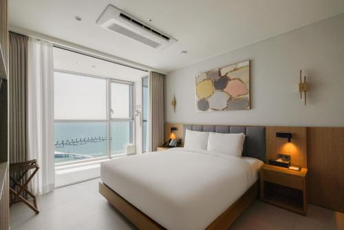 a bedroom with a large white bed and a large window at WAVEM HOTEL west in Siheung