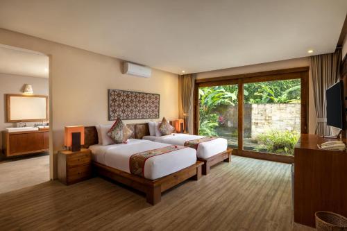 a bedroom with two beds and a large window at Senetan Villas and Spa Resort in Payangan