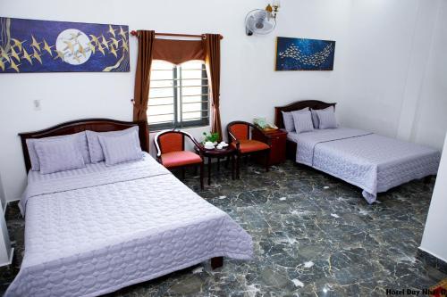 a room with two beds and a table and chairs at HOTEL DUY NHẤT 2 in Phú Nhơn