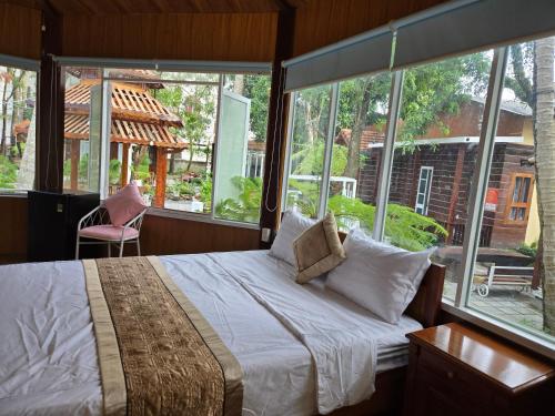 une chambre avec un lit et une grande fenêtre dans l'établissement MangoBungalow, à Hue