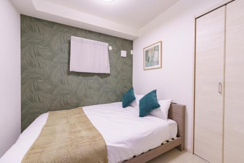 ein Schlafzimmer mit einem weißen Bett mit blauen Kissen in der Unterkunft 6 min to Nagoya Brand-new building Sleeps 5 in Nagoya