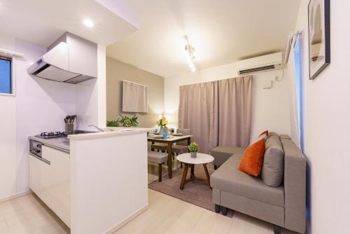 a kitchen and a living room with a couch and a table at 6 min to Nagoya Brand-new building Sleeps 5 in Nagoya