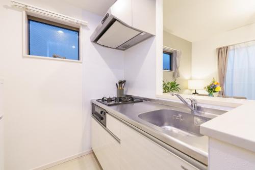 eine weiße Küche mit Spüle und Fenster in der Unterkunft 6 min to Nagoya Brand-new building Sleeps 5 in Nagoya