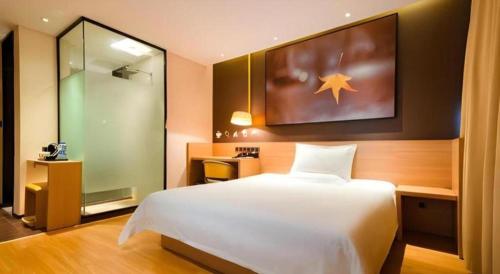 a bedroom with a large white bed and a mirror at IU Hotel Kunming Jinma Bijifang Joy City in Kunming