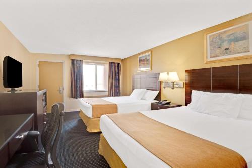 a hotel room with two beds and a television at Super 8 by Wyndham Milford/New Haven in Milford