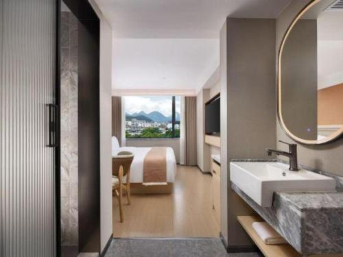 a bathroom with a bed and a sink and a mirror at Immersing Hotel Guilin Two Rivers and Four Lakes Dongxi Alley in Guilin