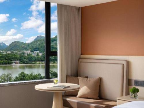 a room with a bed and a table and a window at Immersing Hotel Guilin Two Rivers and Four Lakes Dongxi Alley in Guilin