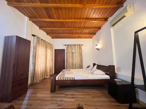 a bedroom with a bed and a wooden ceiling at VillaWatuna in Unawatuna