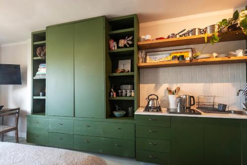 Una cocina con gabinetes verdes y un fregadero. en Vibey Kloof Street Retreat, en Ciudad del Cabo