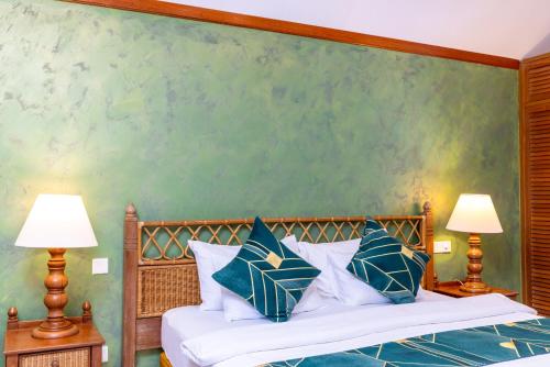 a bedroom with a bed with blue and white pillows at Fihalhohi Maldives in South Male Atoll