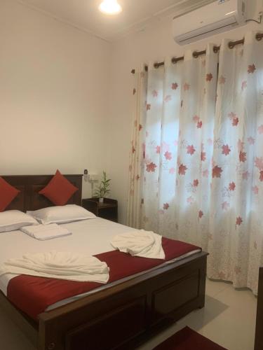 a bedroom with a bed with red sheets and curtains at Captain's Ridge in Nattarampota