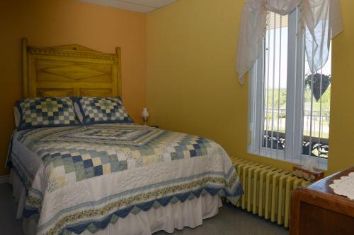 a bedroom with a bed and a window at Gîte Grand-Père Nicole in Val-Brillant
