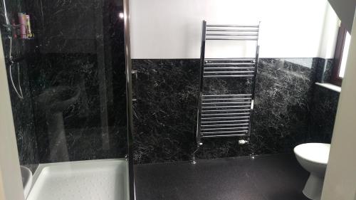 a bathroom with a shower with a black marble wall at The Boat House Guesthouse in Boat of Garten