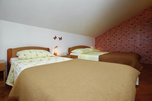 a bedroom with two beds and a brick wall at Apartments Vila Ana in Seline