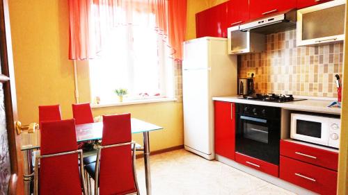 cocina con armarios rojos y nevera blanca en Apartments Tiraspol en Tiraspol