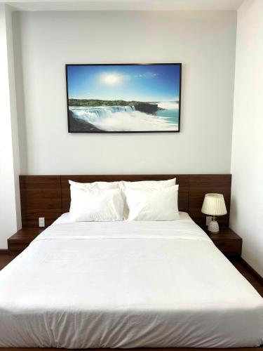 a bedroom with a white bed with a picture on the wall at Hotel ĐÁ ĐỎ in Da Nang
