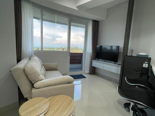 a living room with a couch and a chair and a television at The Nove Apartment Kalani Tower Sea View in Pulau Nongsa