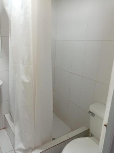 a white bathroom with a shower and a toilet at Hosp Sophie in Cusco
