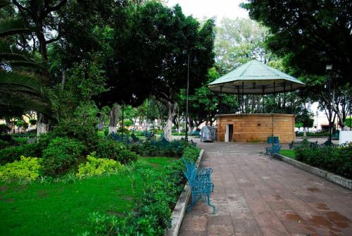 un parc avec des bancs bleus et un parasol dans l'établissement Hotel MS, à Cholula