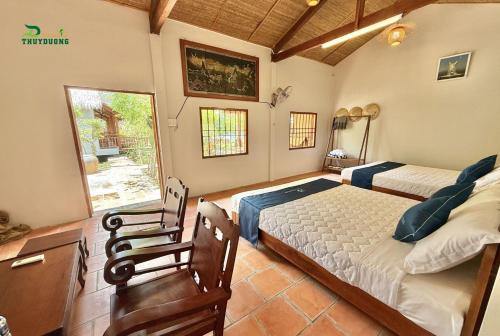 a bedroom with two beds and a desk and a window at Homestay Thùy Dương 2 in Cai Be