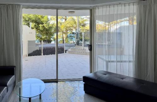 a living room with a black couch and a glass table at ZANZ205- Exclusive Outdoor Spa with Ocean Glimpses in Mooloolaba