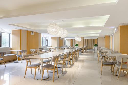 uma longa sala de jantar com mesas e cadeiras em JI Hotel Beijing Yizhuang Economic Development Zone em Pequim