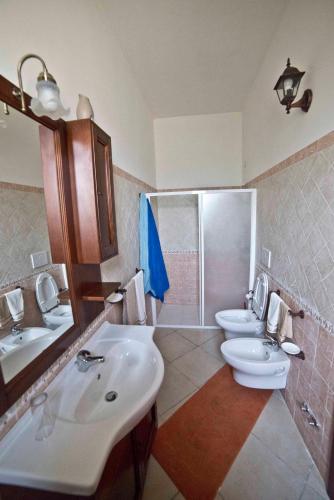 a bathroom with two sinks and a toilet and a mirror at Masseria Cinti in Bagnolo del Salento