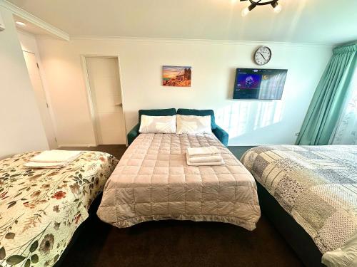 a bedroom with two beds and a clock on the wall at Modern Private Deluxe Master Suite California Bed and Bathtub in Auckland