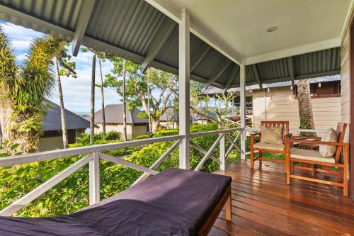 a porch of a house with a bed and a chair at Iririki Island Resort & Spa in Port Vila
