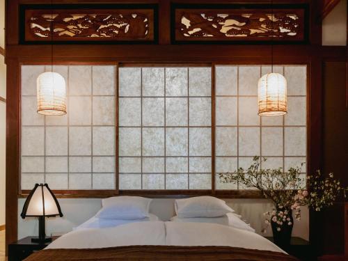 a bedroom with a bed with two lamps and a window at LA TERRA narai in Shiojiri