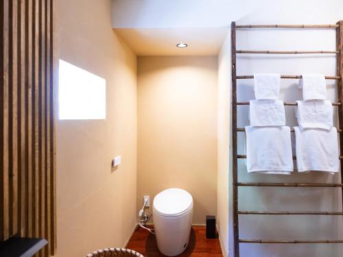 a bathroom with a toilet and towels on a towel rack at LA TERRA narai in Shiojiri