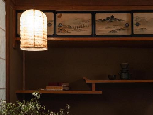 a lamp hanging over a shelf with pictures on it at LA TERRA narai in Shiojiri