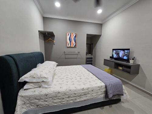 a bedroom with a bed and a flat screen tv at Laman D'Village in Kelebang Besar