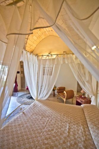 a bedroom with a canopy bed with white curtains at Masseria Cinti in Bagnolo del Salento