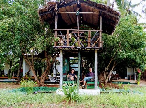 a man and woman sitting in a tree house at Lake Wind in Habarana